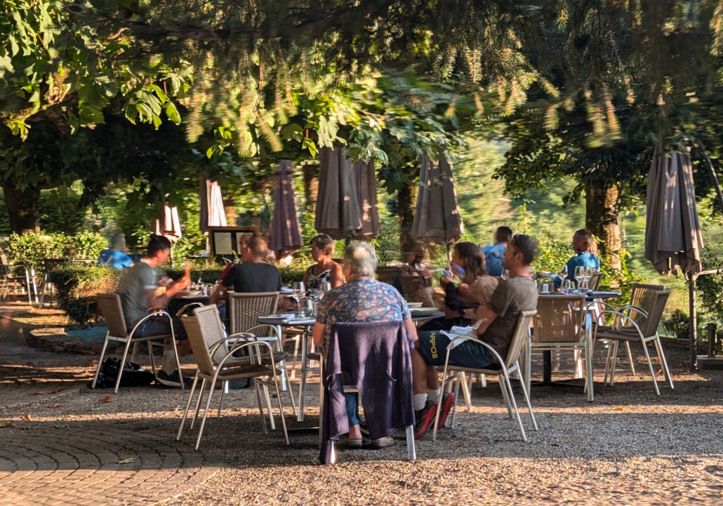 Nouvelle terrasse de l'Hôtel Les Mésanges à Saint-Martin-d'Uriage, offrant un espace convivial et chaleureux sous les arbres, parfait pour se détendre et profiter de la nature environnante